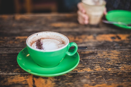 A green cup of a coffee on a wooden table